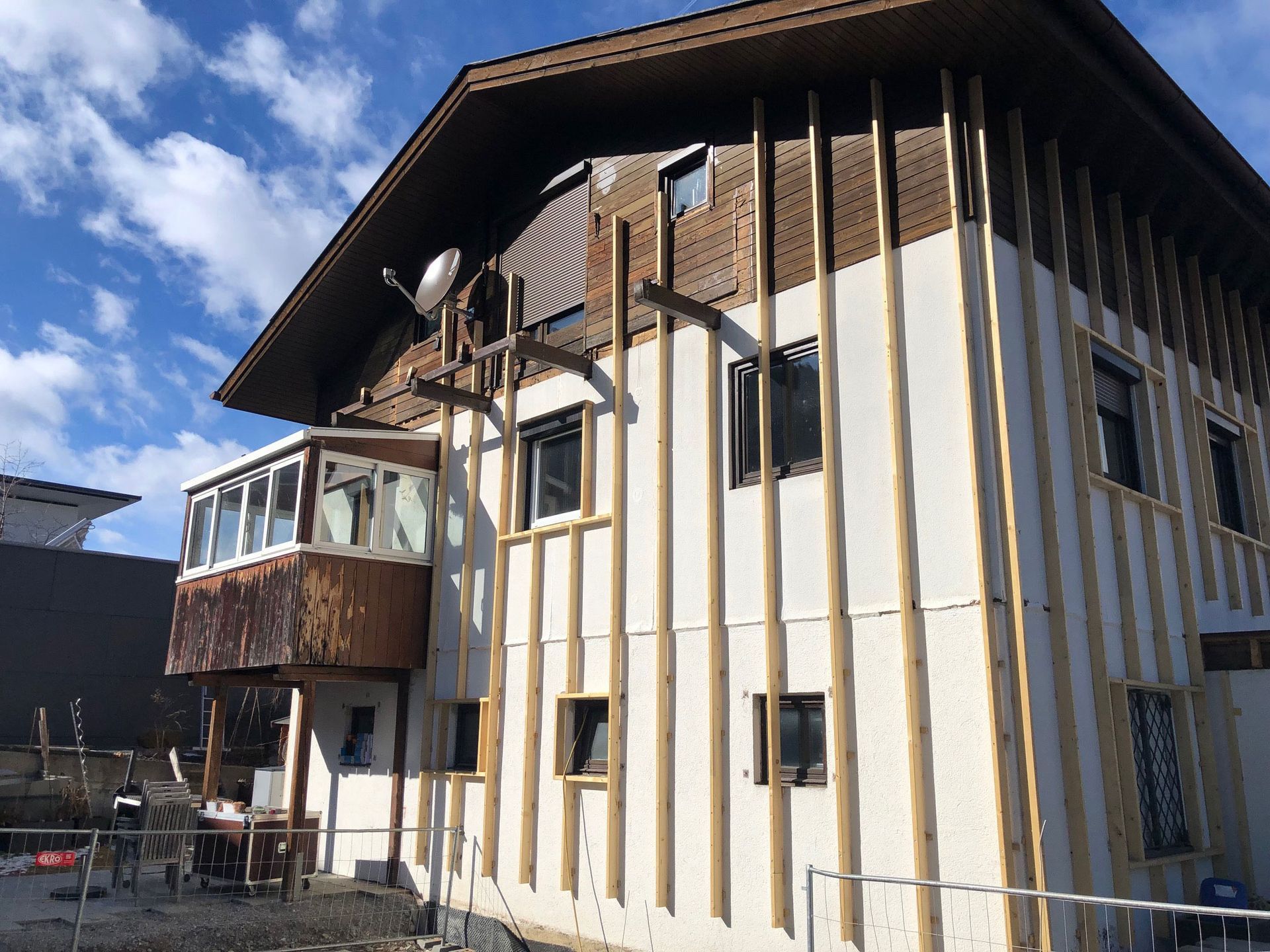 Wooden chalet-style house with vertical siding and a balcony under a blue sky
