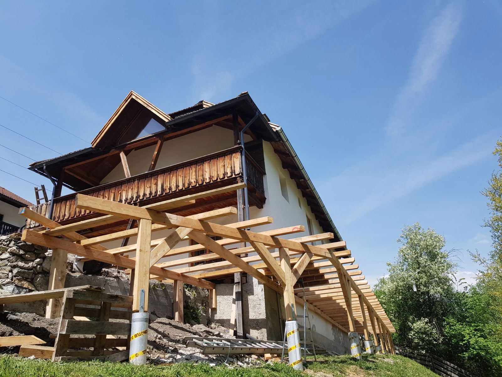 Wooden house on stilts with exposed framing under construction beneath a blue sky