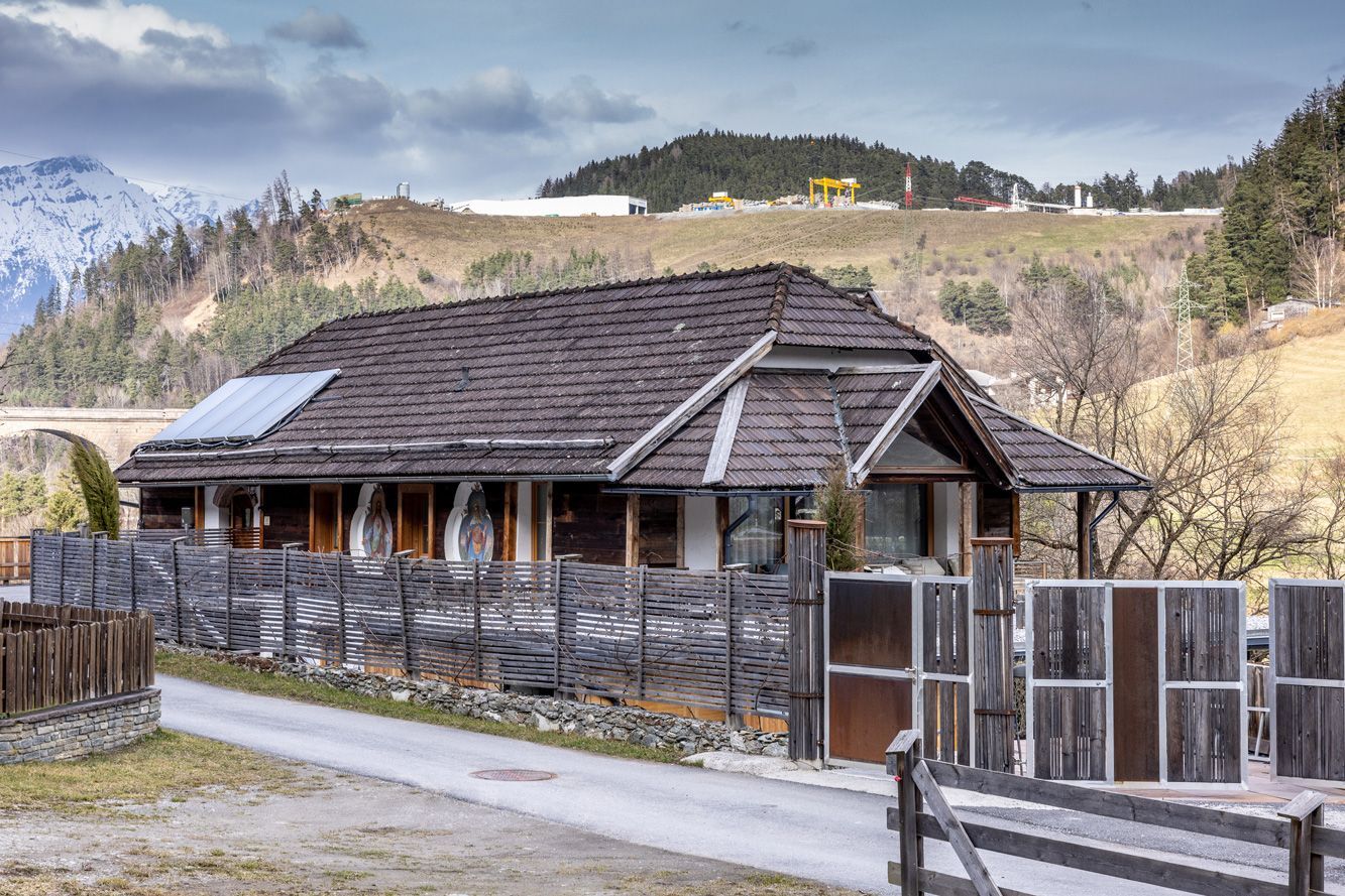 Rustic wooden house with a fenced yard on a cloudy hillside landscape