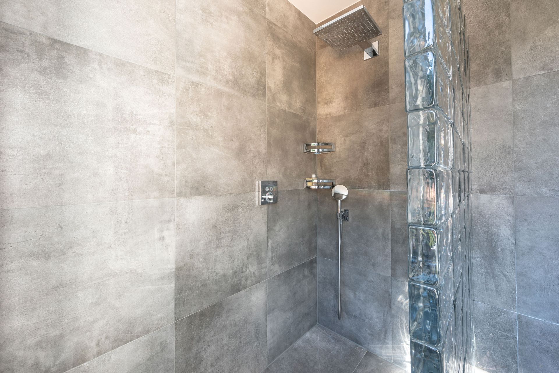 Gray tiled shower with rain showerhead and handheld wand