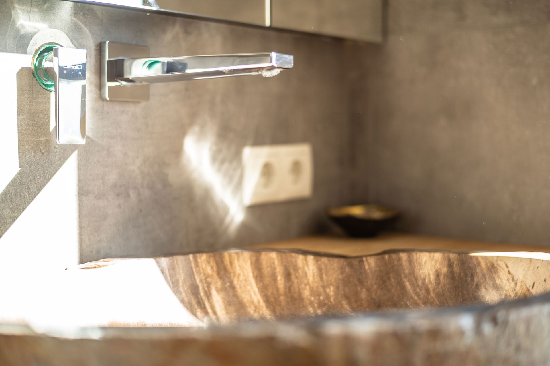 Chrome faucet over a wooden sink in a sunlit bathroom