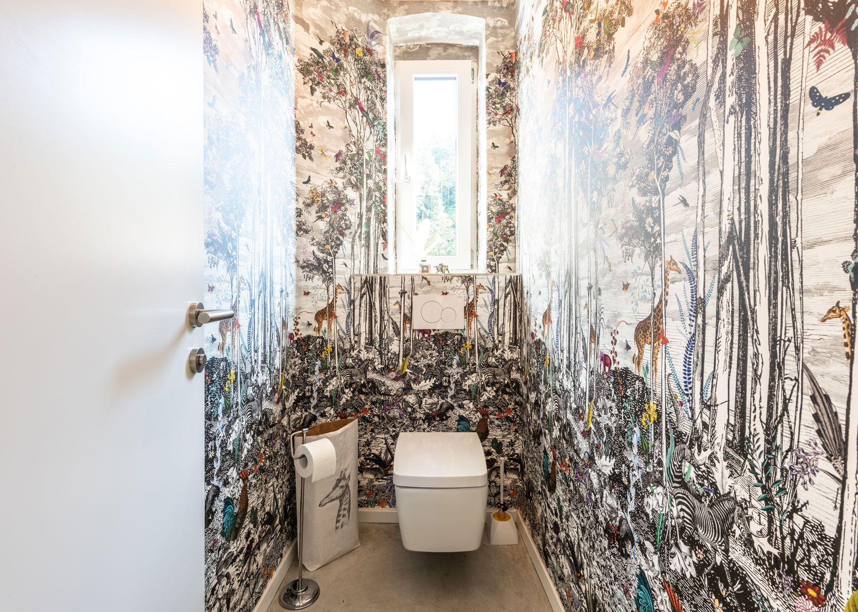 Small bathroom with toilet, sink, and walls covered in dense black-and-white mural art.