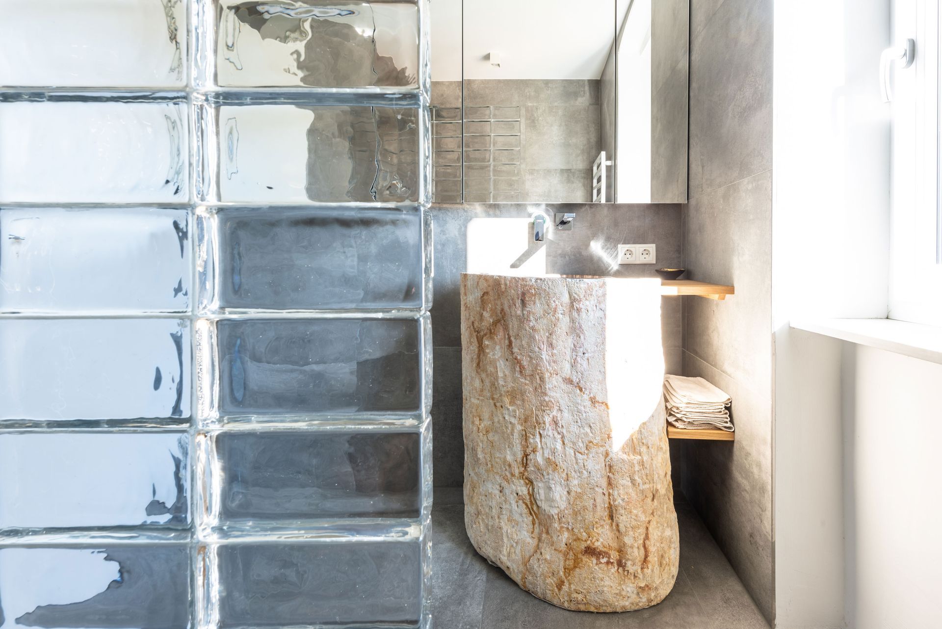 Modern bathroom with frosted glass wall and stone sink near a window