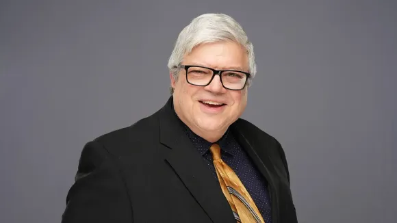 A man in a suit and tie is smiling for the camera.