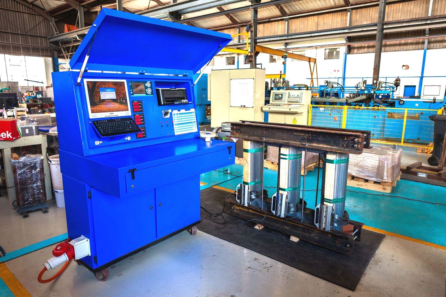 a blue machine in a factory with a computer on it