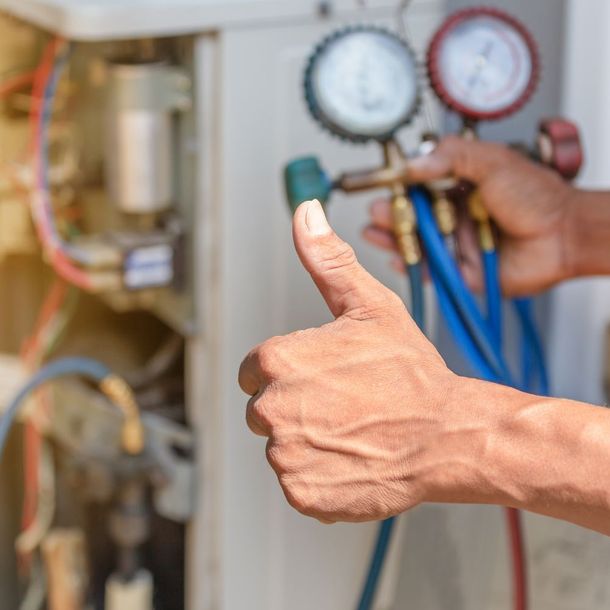 a person is giving a thumbs up while working on an air conditioner .