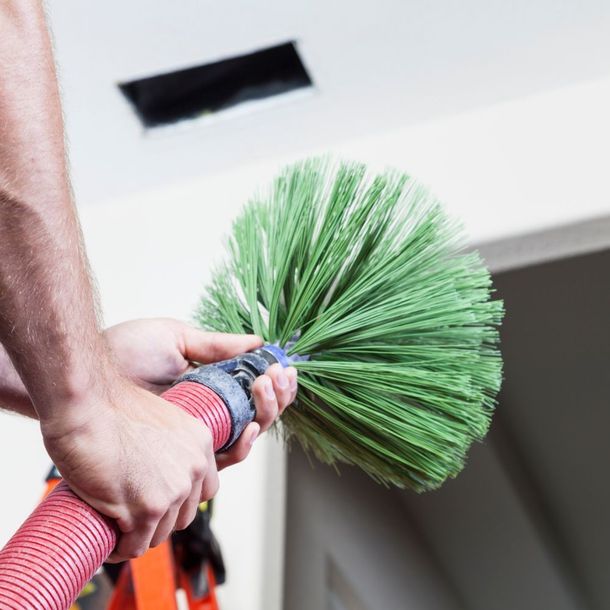 a person is holding a hose with a green brush attached to it .