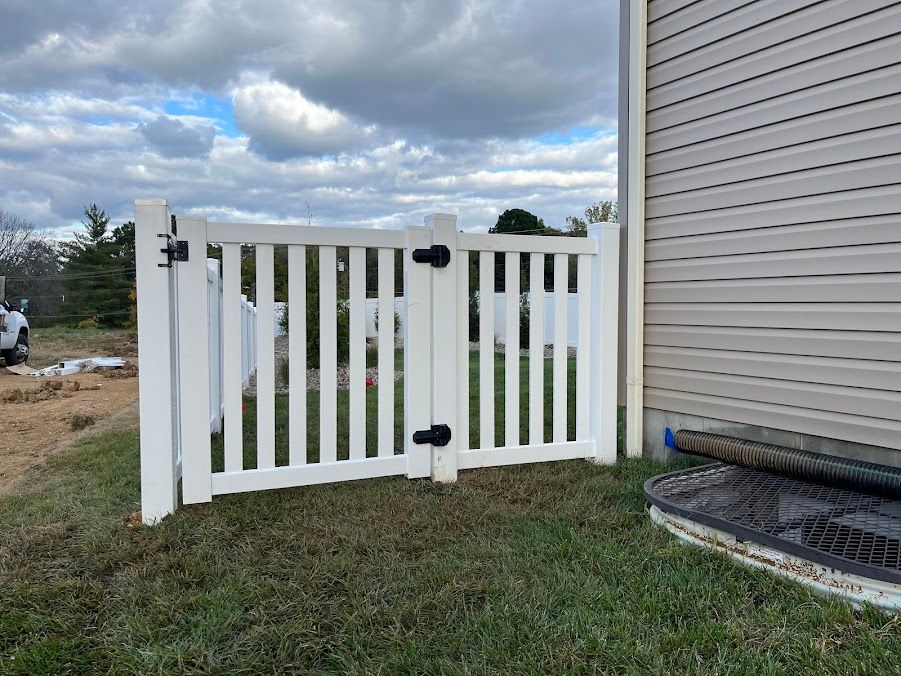 A white fence is sitting next to a house.