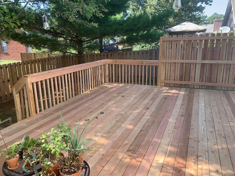 A wooden deck with a fence and potted plants on it.