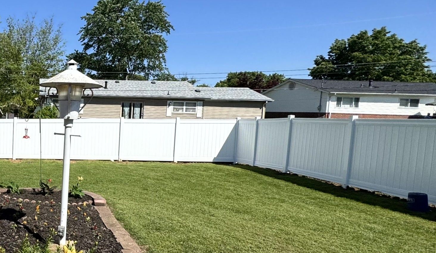 Black metal fence with small gate, green grass, and a building in the background.