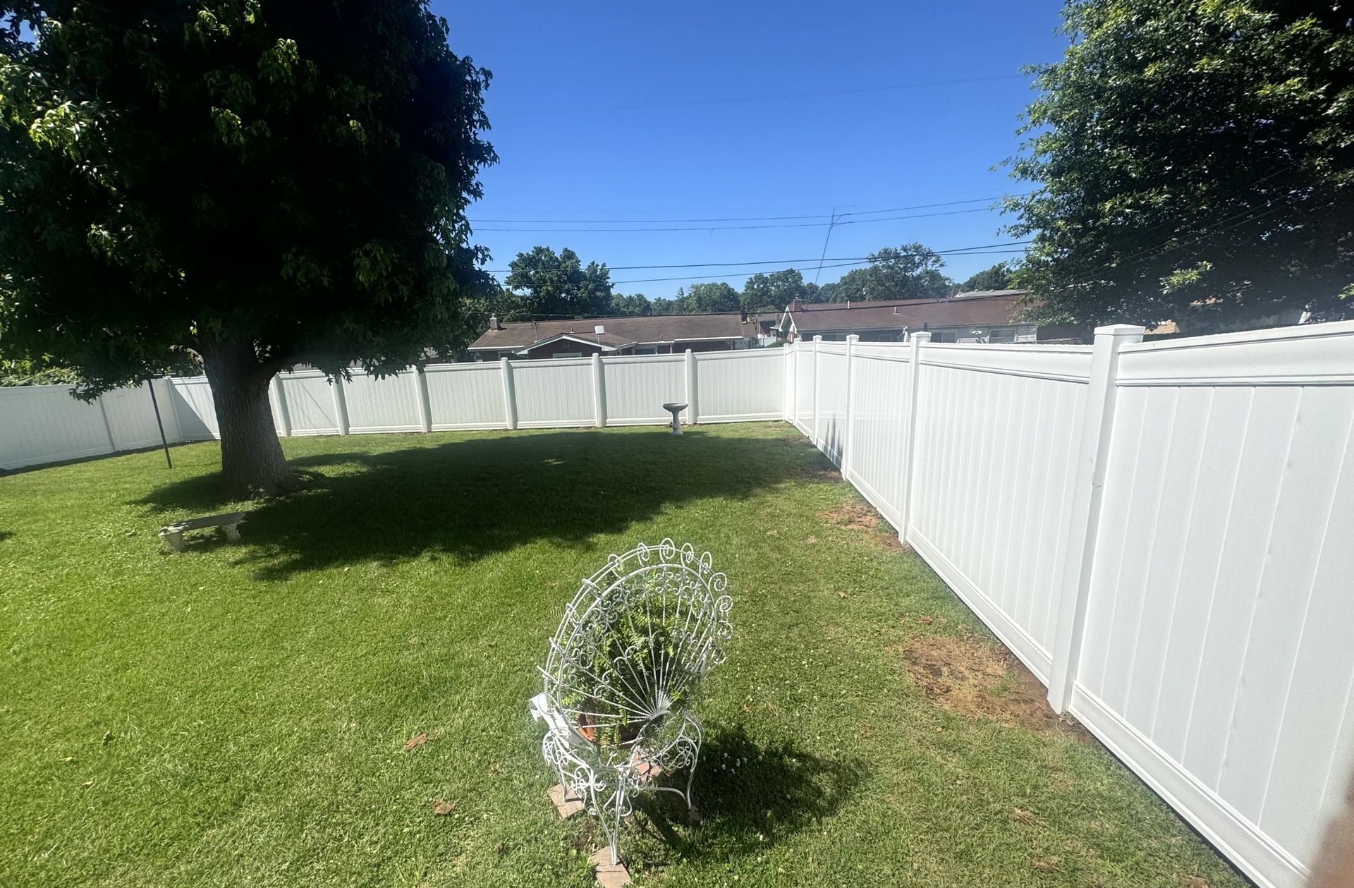 Black metal fence with small gate, green grass, and a building in the background.