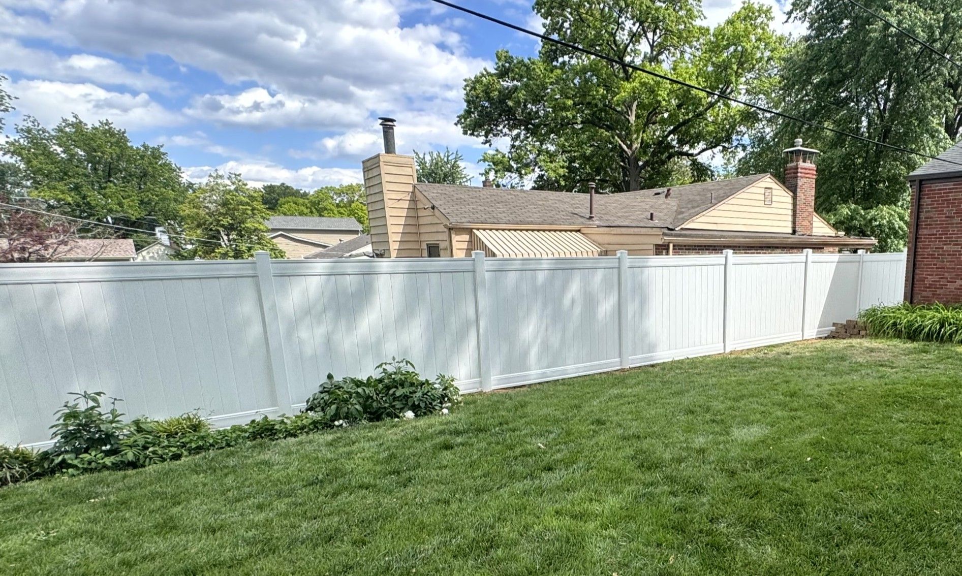 Black metal fence with small gate, green grass, and a building in the background.