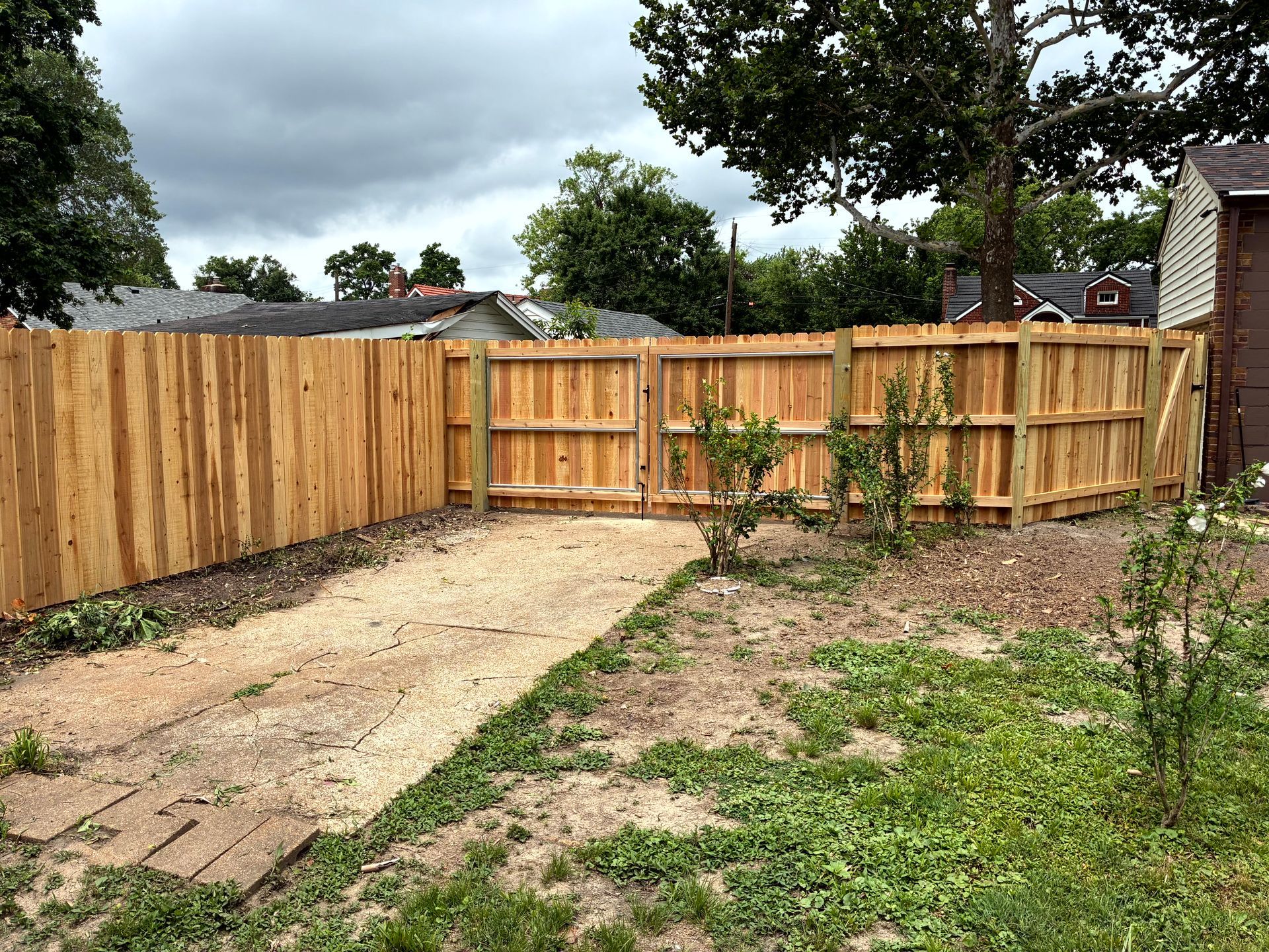 Wooden fence enclosing a yard with a gravel pathway leading to a double gate.