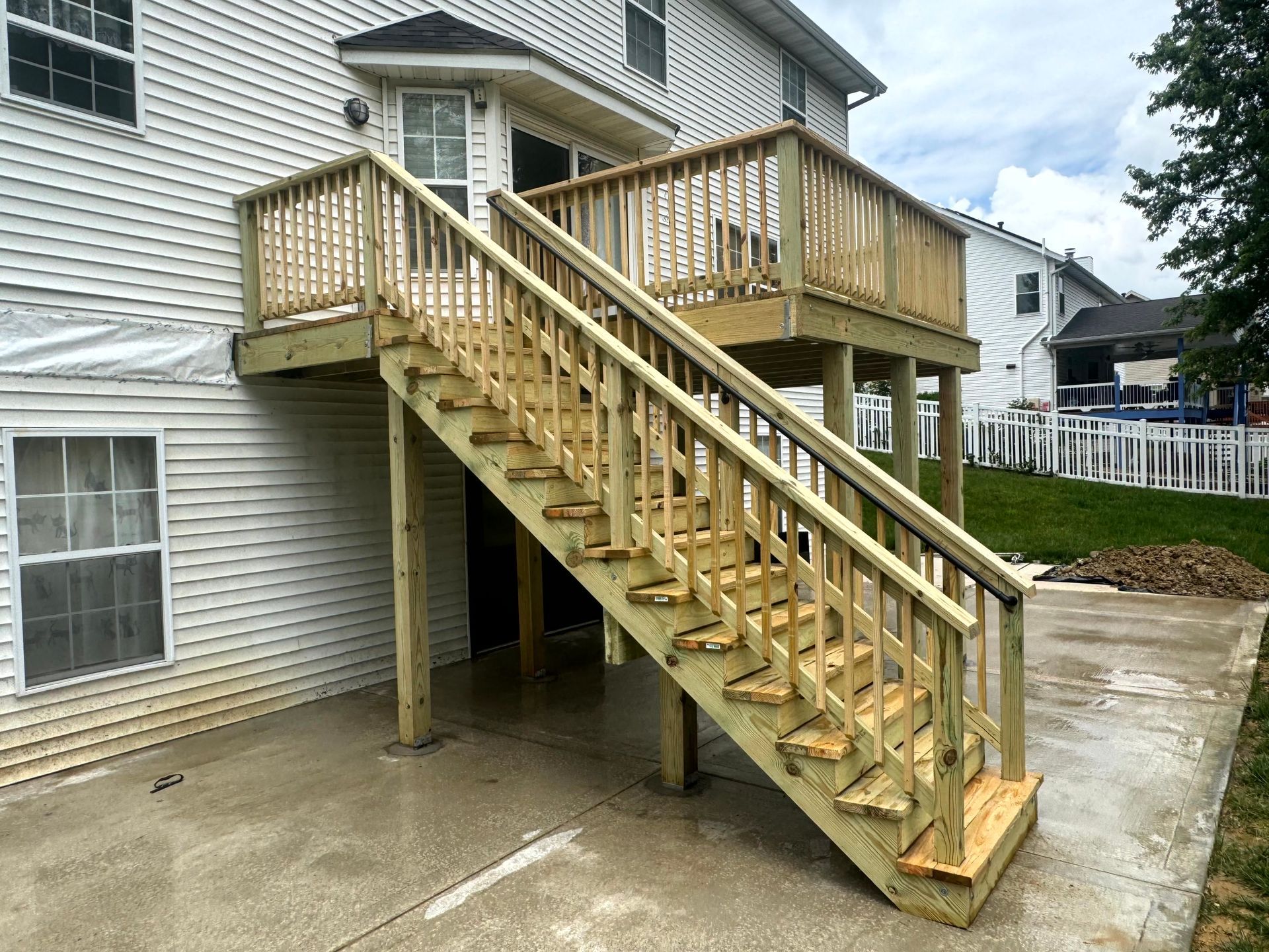 A wooden deck with a fence and potted plants on it.