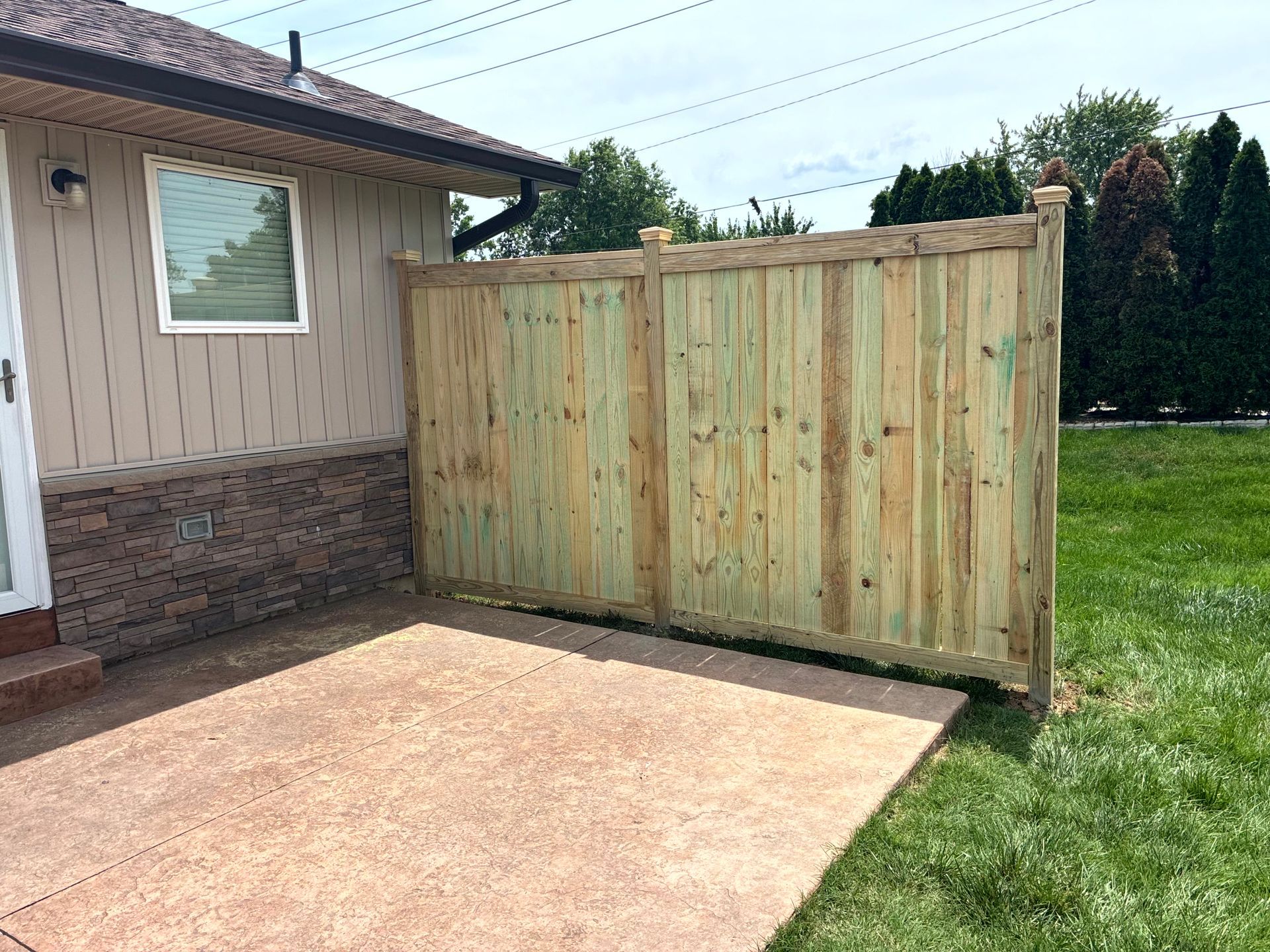 Black metal fence with small gate, green grass, and a building in the background.