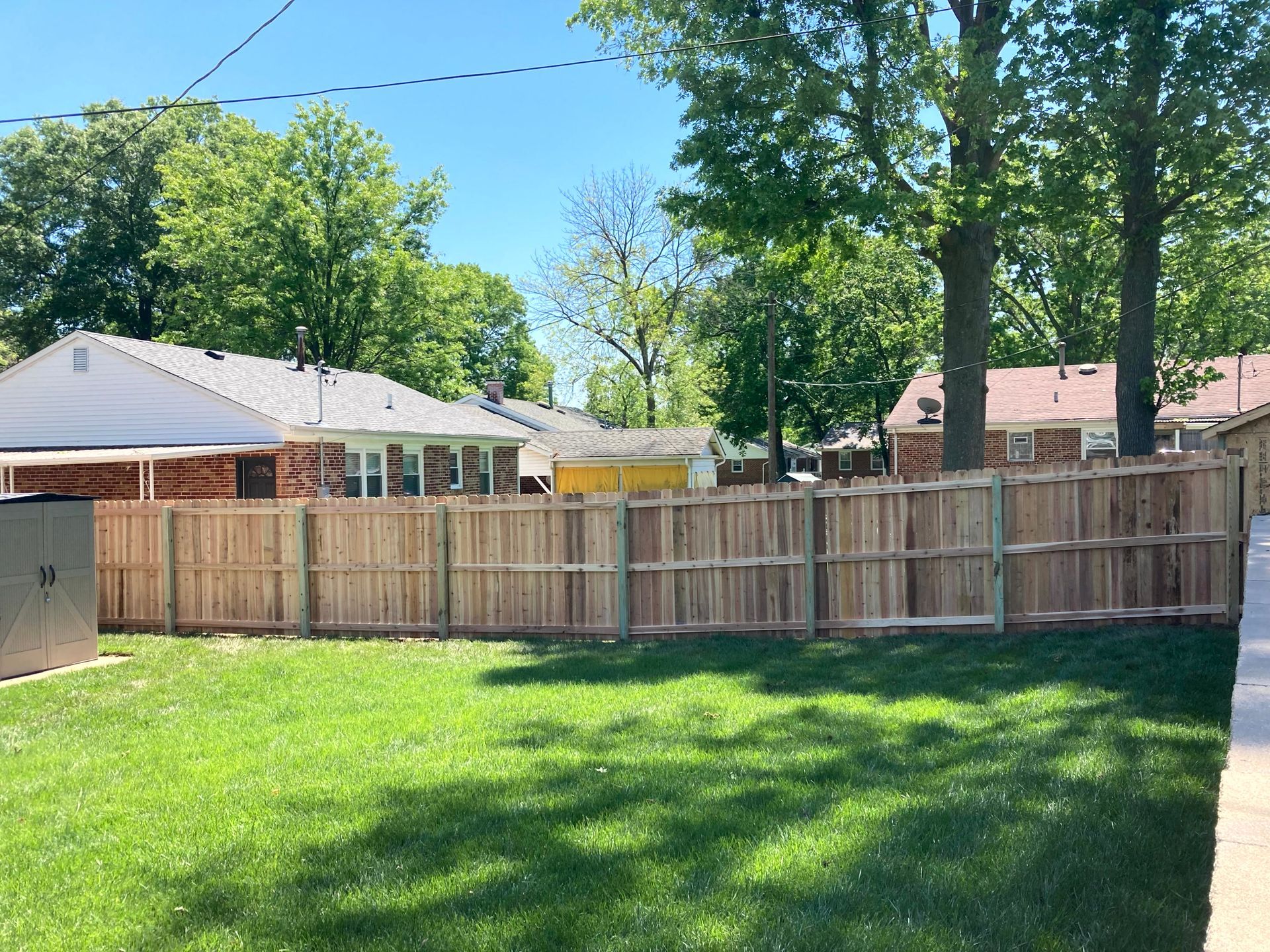 Black metal fence with small gate, green grass, and a building in the background.