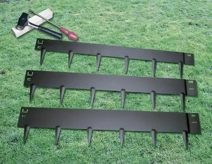 Three black metal garden tools on grass, with a hand trowel and pruner at top left.