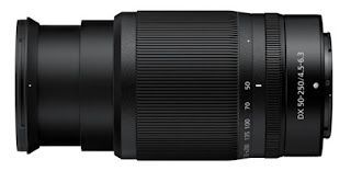A close up of a camera lens on a white background lying on its side and facing to the left.