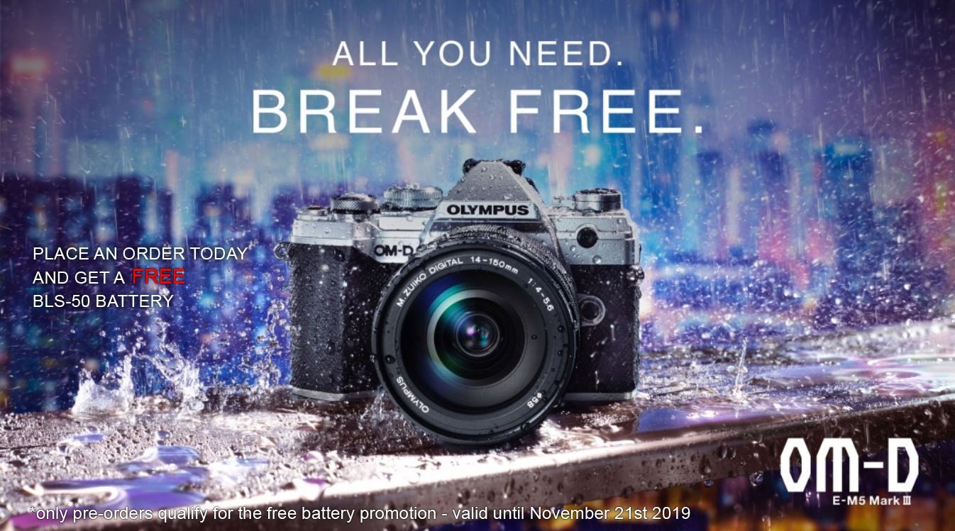 An advertisement for an OM-D OM-System camera, featuring a camera sitting on top of a wall ledge, with heavy rain pouring down on it. On the banner is teaxt that says
