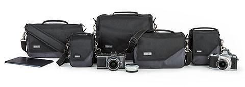 A group of camera bags and cameras are sitting next to each other on a white background.