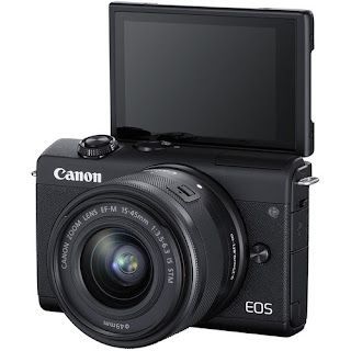 A canon eos camera with its video finder opened and facing up, is sitting on a white surface.