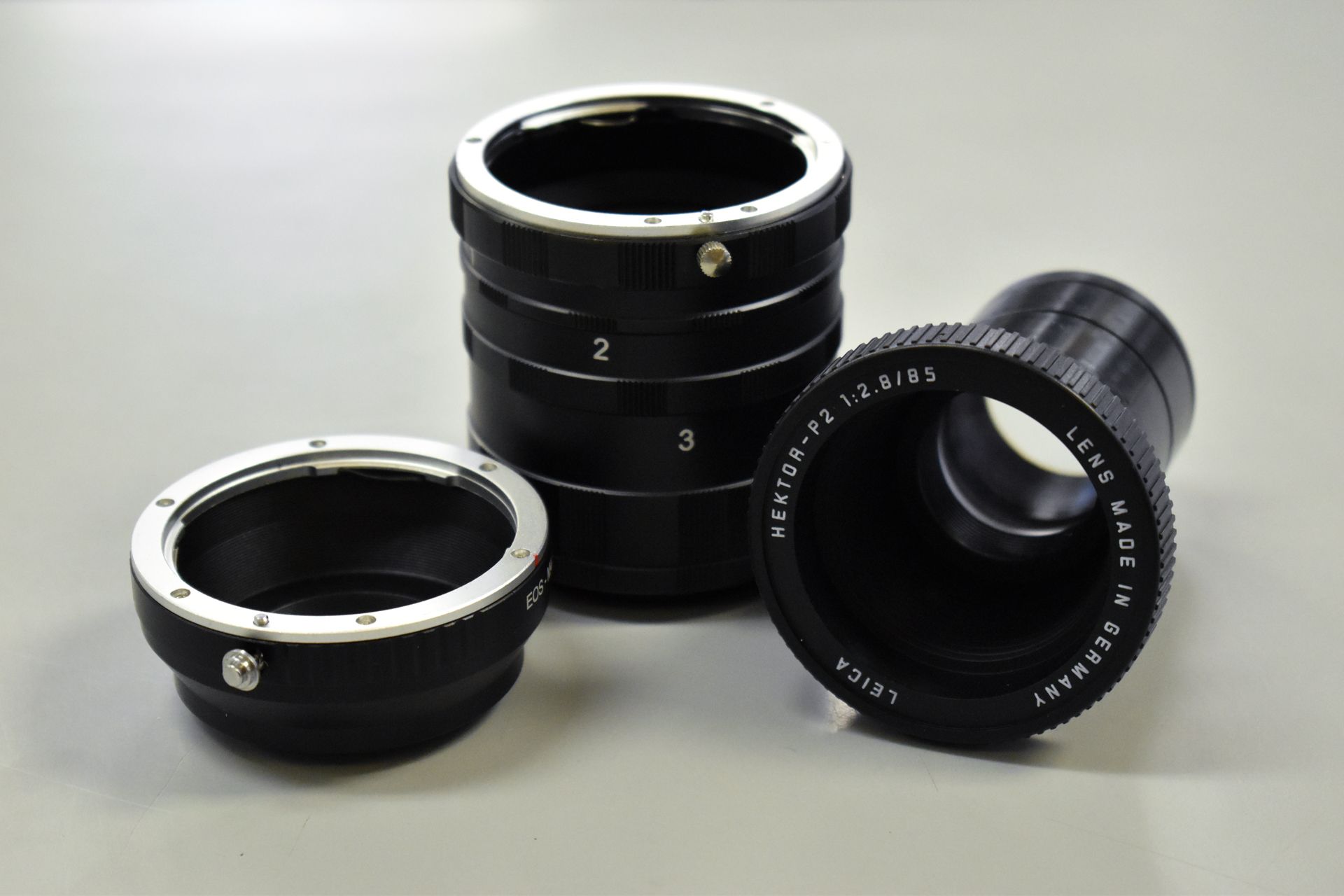 A stack of 3 leica lens rings on a grey table.
