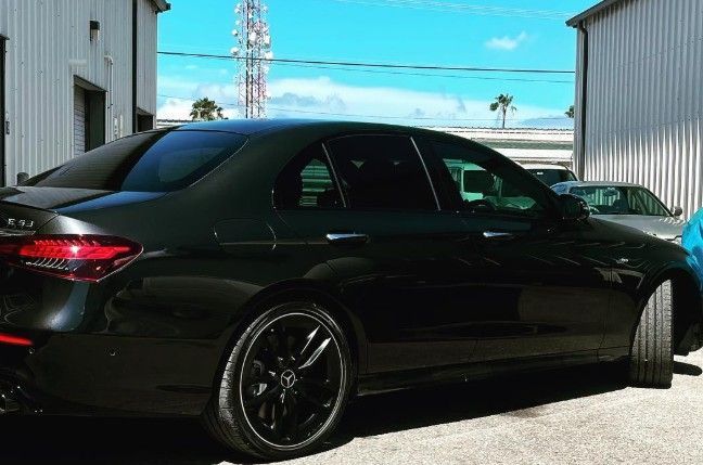 Black sedan with tinted windows parked outside, sunny day.