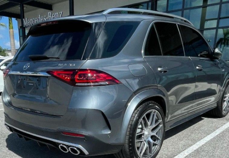 Gray Mercedes-Benz GLE SUV parked outside a dealership, rear view.