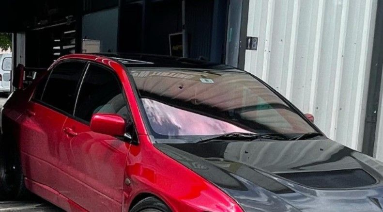 Red and black Mitsubishi Lancer Evolution parked in front of a building.