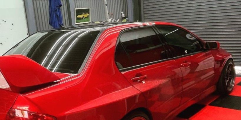 Red sports car with a black roof and a large spoiler.
