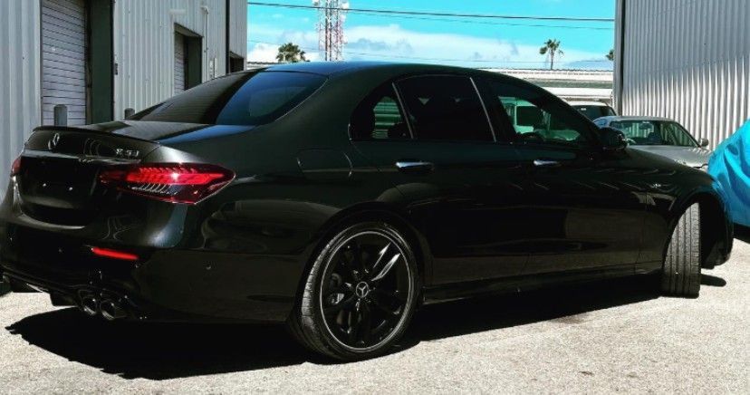 Black Mercedes-AMG E63 sedan parked outdoors with tinted windows and black rims.
