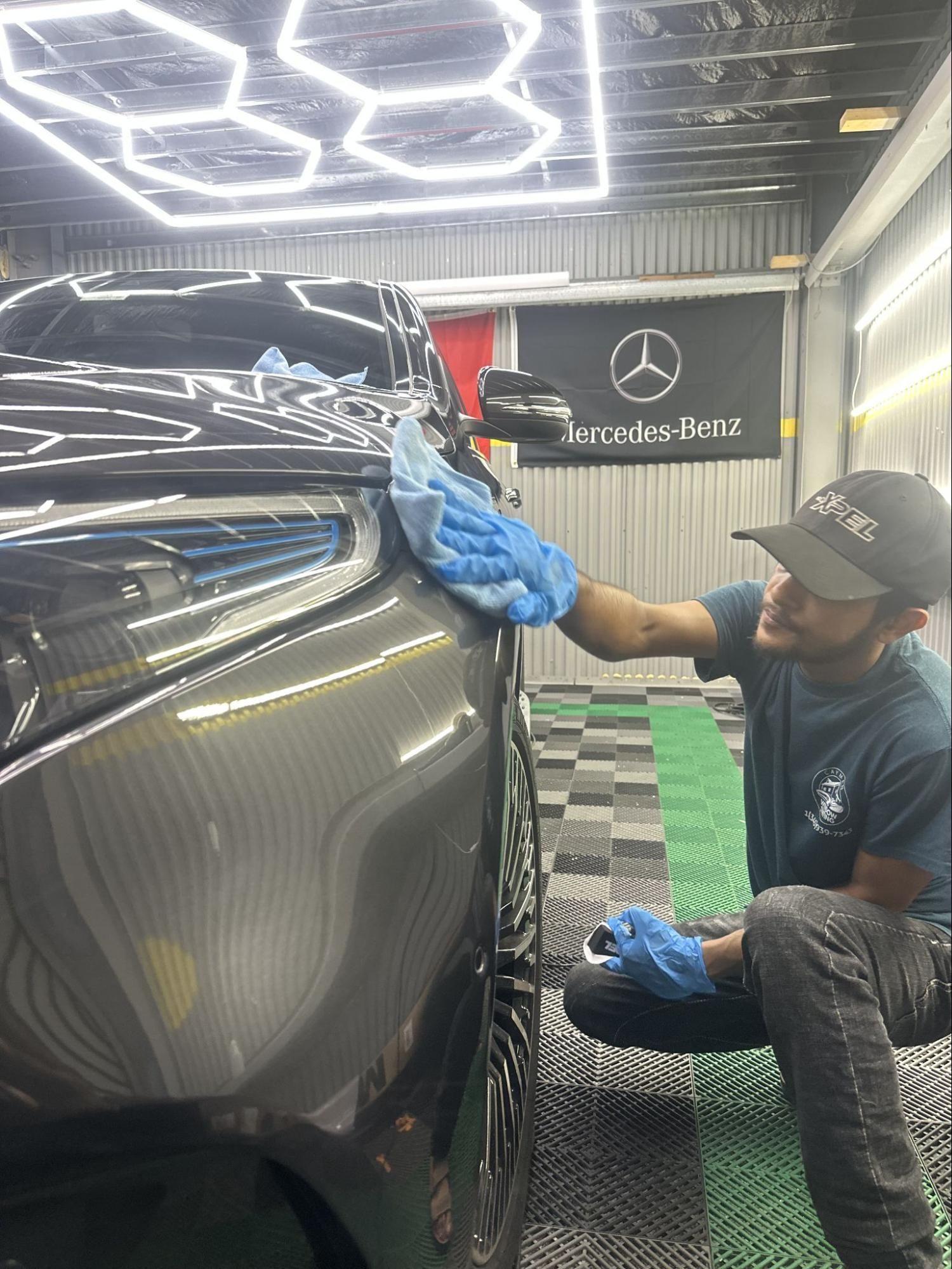 A man is cleaning a car with a towel in a garage.