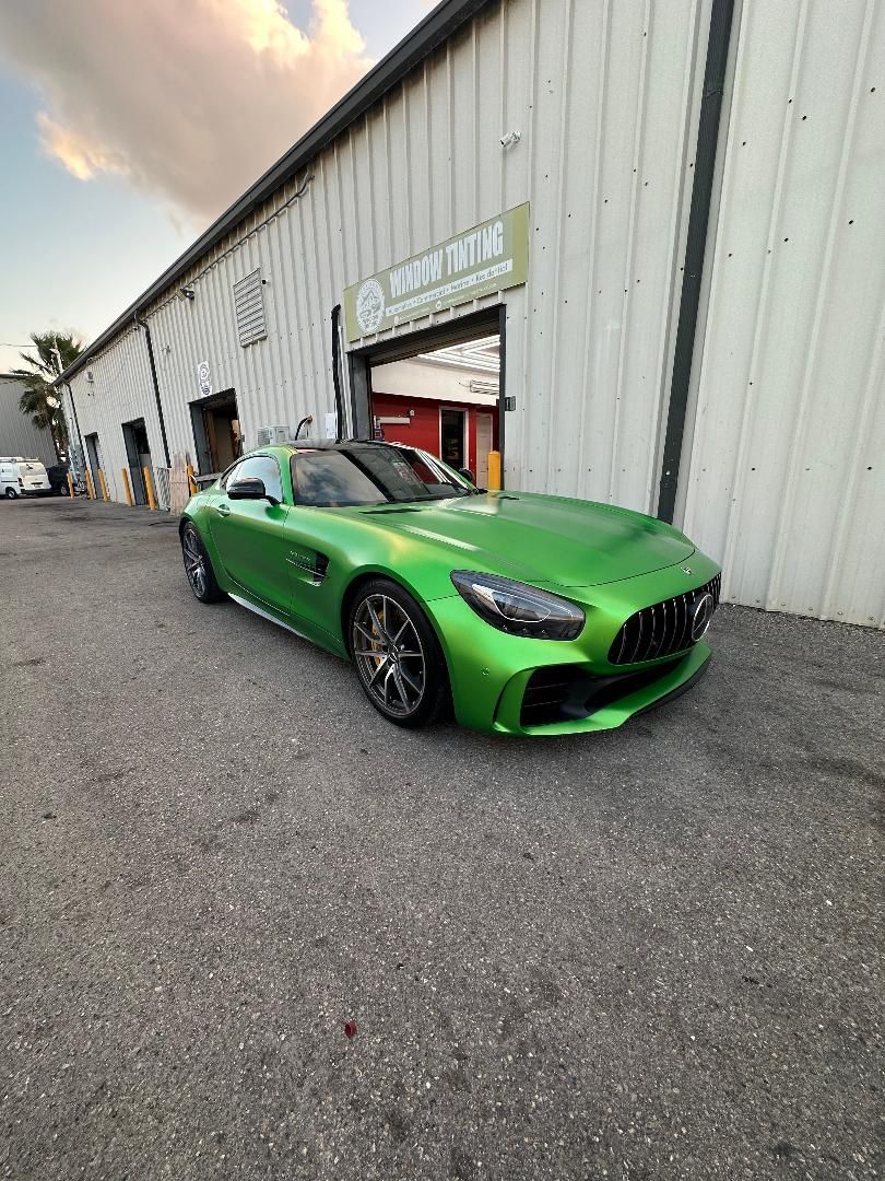 Bright green sports car parked in front of a building with an open doorway.