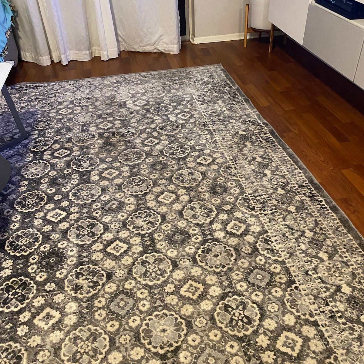 Gray patterned rug on a wood floor in a room.