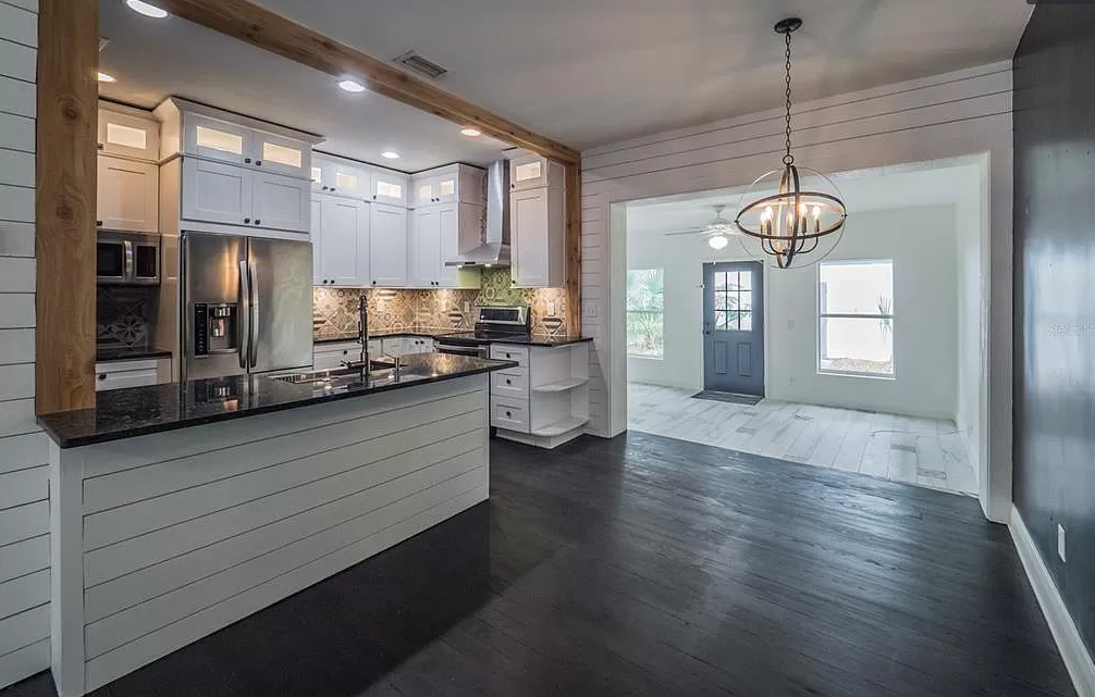 Kitchen and dining area with white cabinets, dark floors, and open doorway.