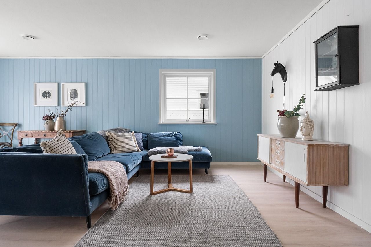 Blue living room with a sectional sofa, rug, and light wood flooring.
