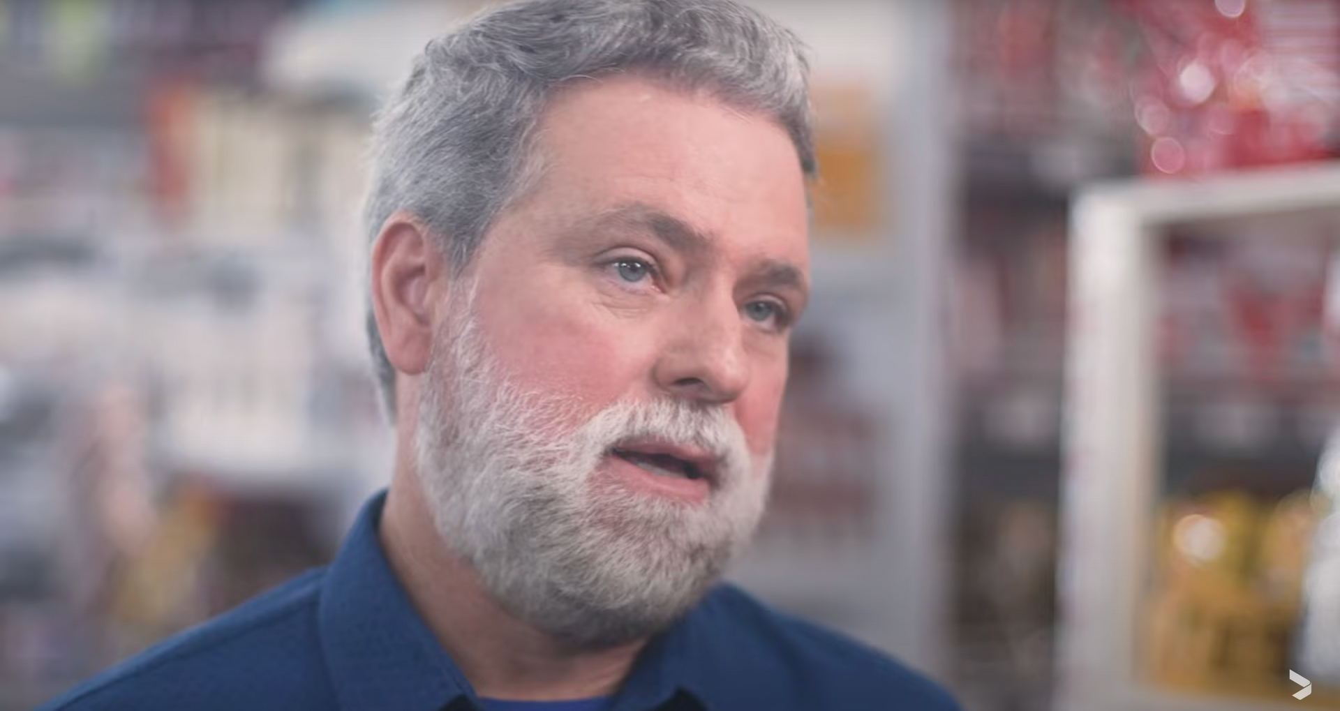 Um homem com barba está conversando com alguém em uma loja.