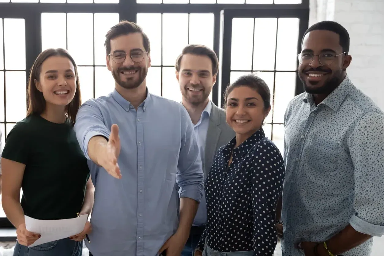 Um grupo de pessoas está próximo um do outro e apertando as mãos.