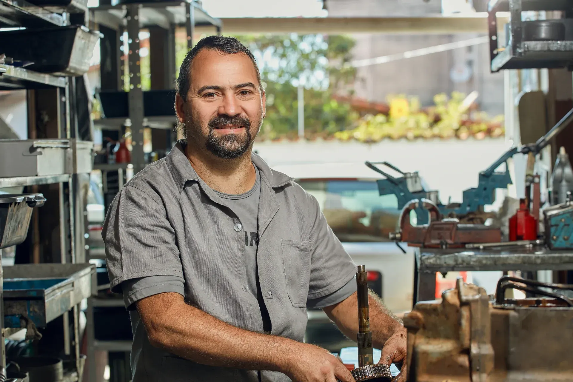 Um homem está em uma garagem trabalhando em uma máquina.