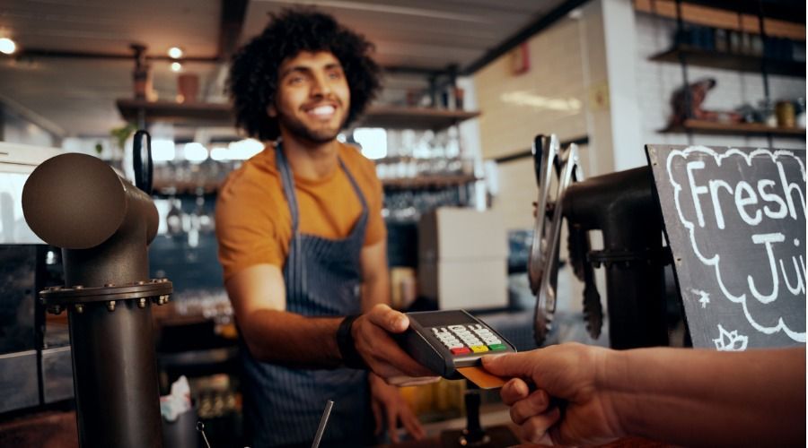 Um homem está dando um cartão de crédito a um cliente em um restaurante.