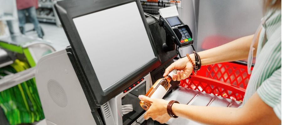 Uma mulher está usando uma máquina de checkout automático em um supermercado.