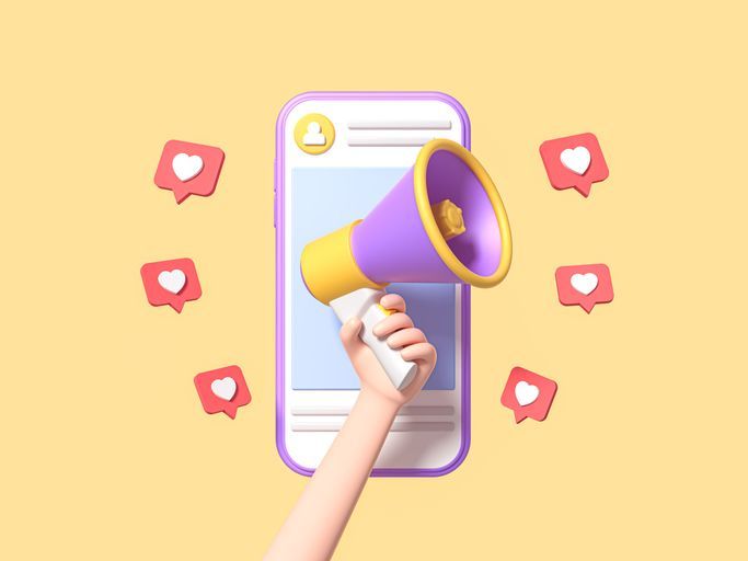 Uma mão segura um megafone na frente de um telefone celular.