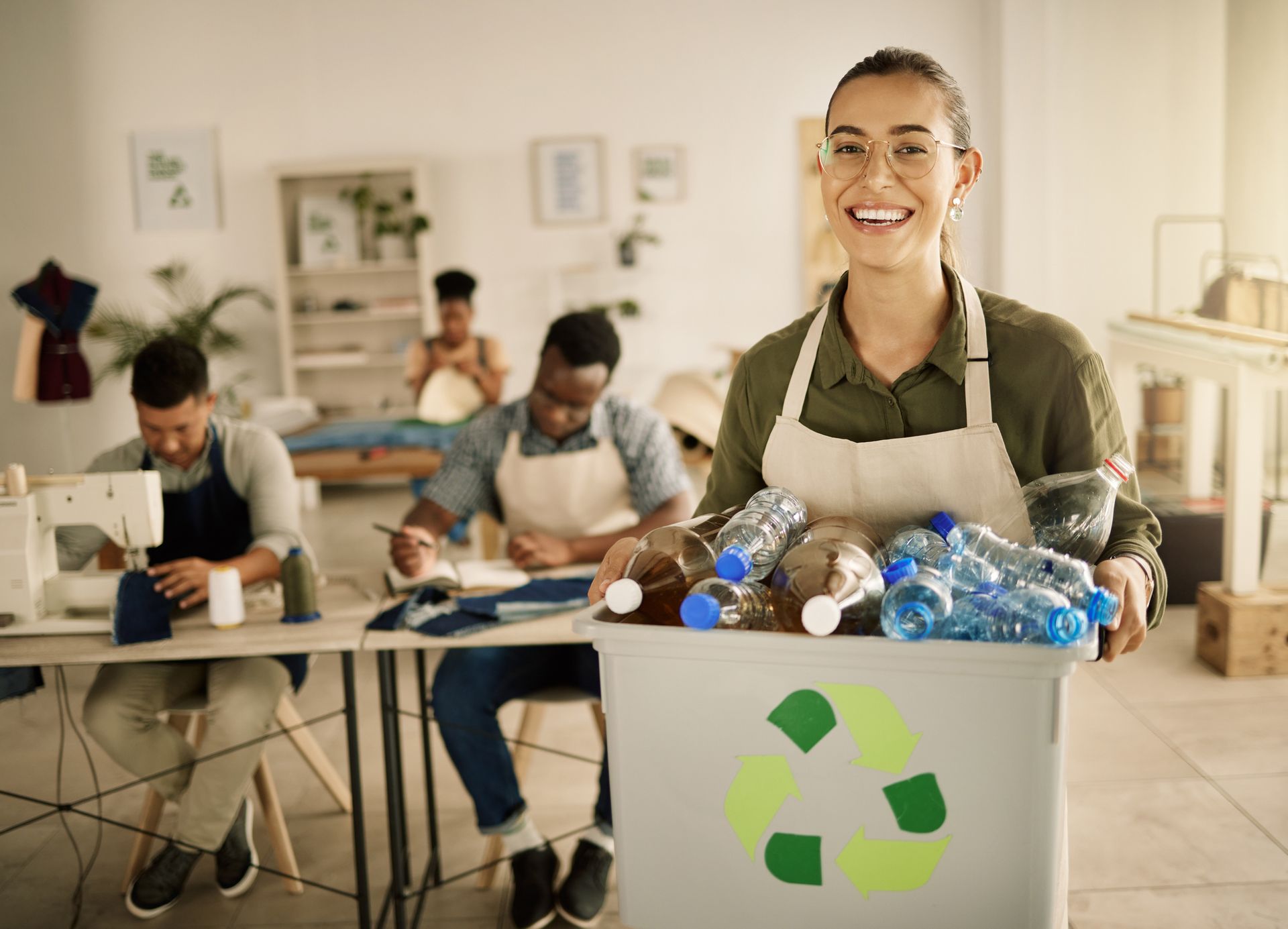 Uma mulher está segurando uma caixa com garrafas prontas para reciclagem.