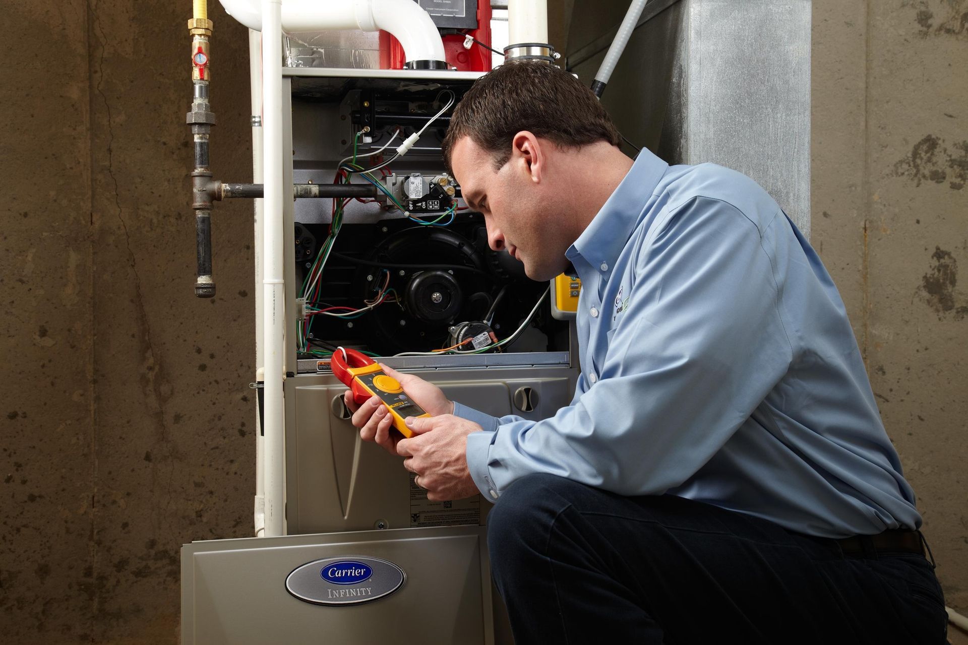 Technician inspecting a furnace with a multimeter in a basement utility room