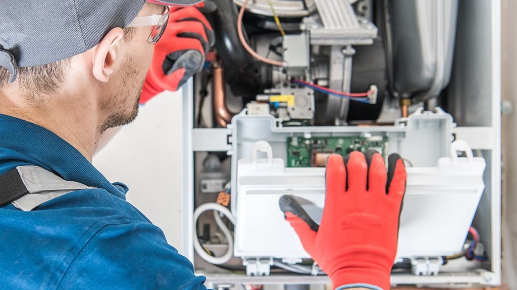 Technician in red gloves inspecting an open electrical panel inside machinery