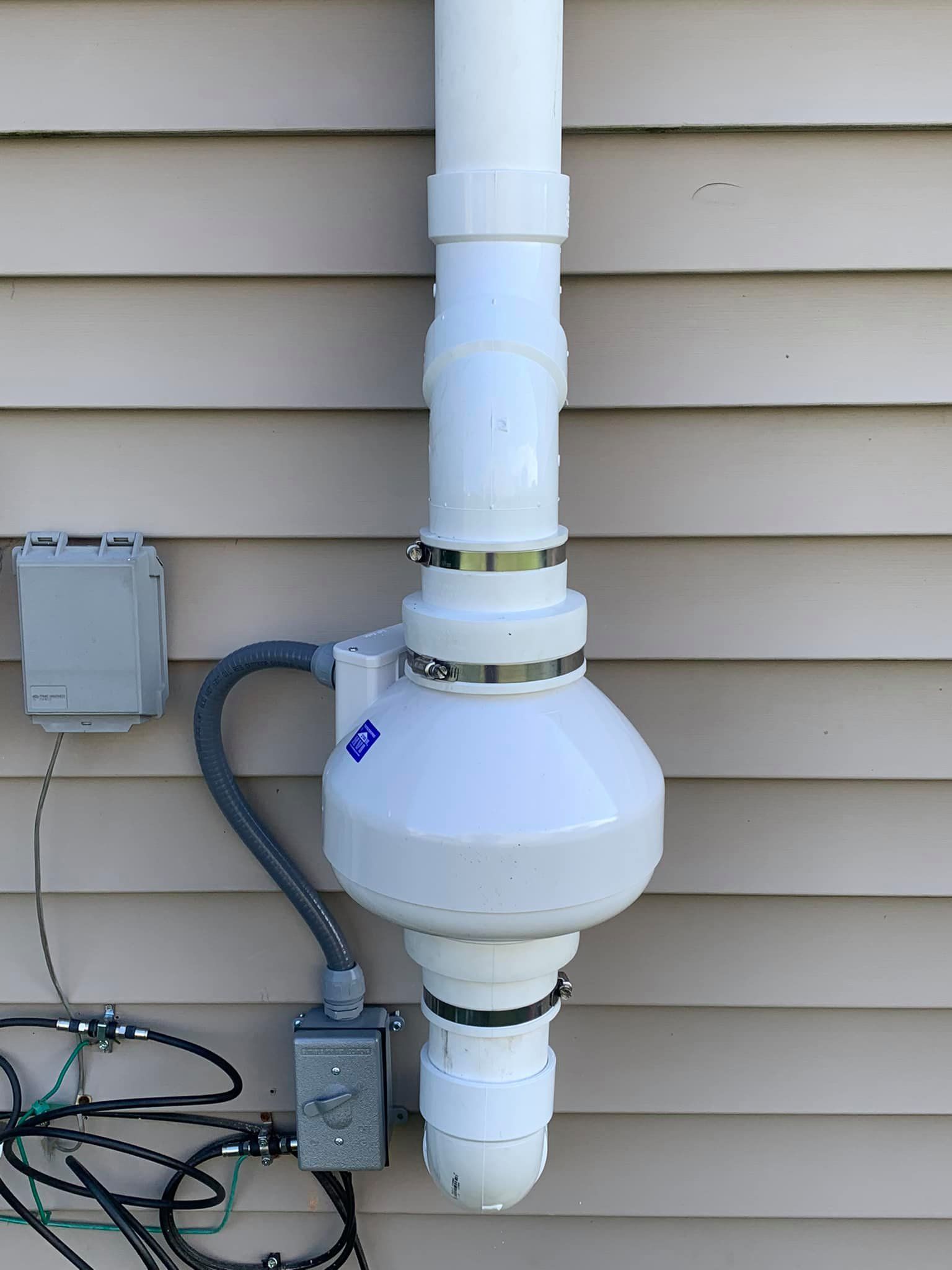 A white pipe is attached to the side of a house.