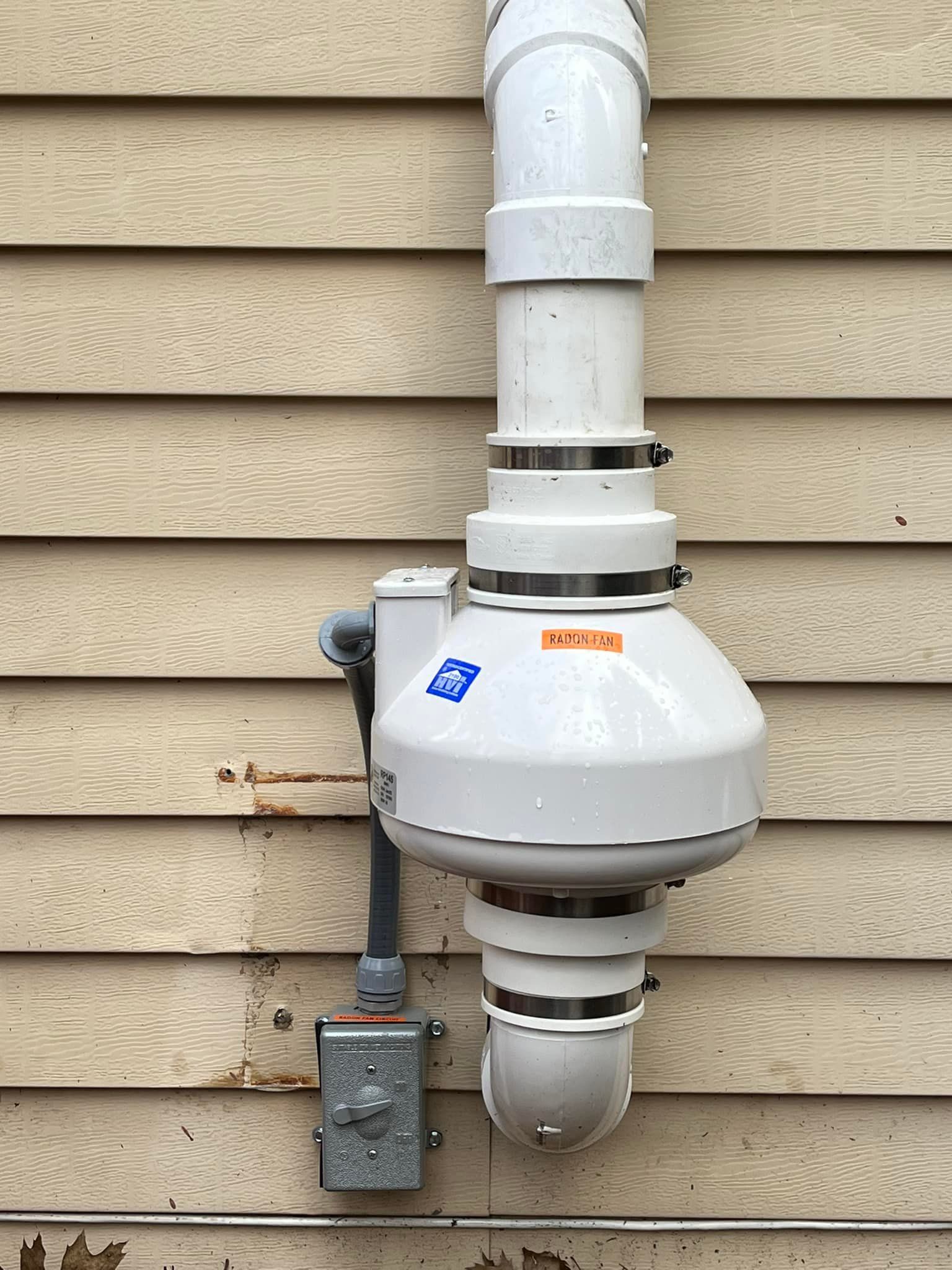 A white pipe is attached to the side of a house.