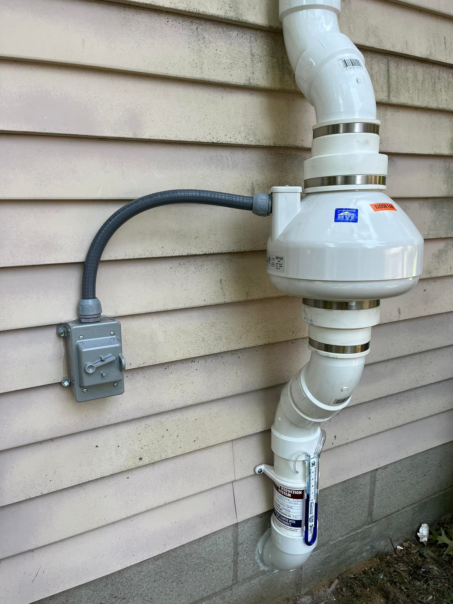 A white pipe is attached to the side of a house.