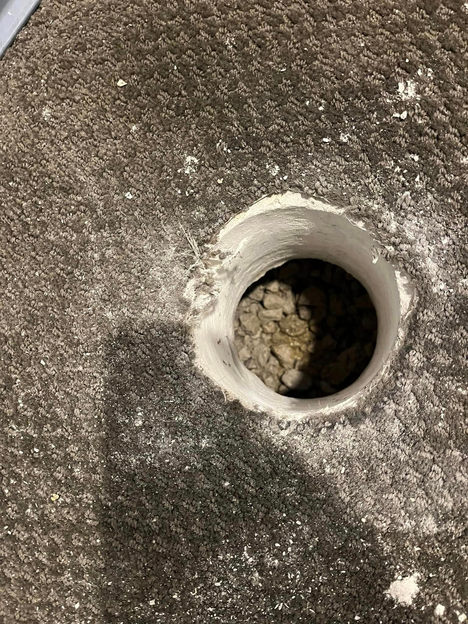 There is a hole in the carpet that looks like a hole in the ground.