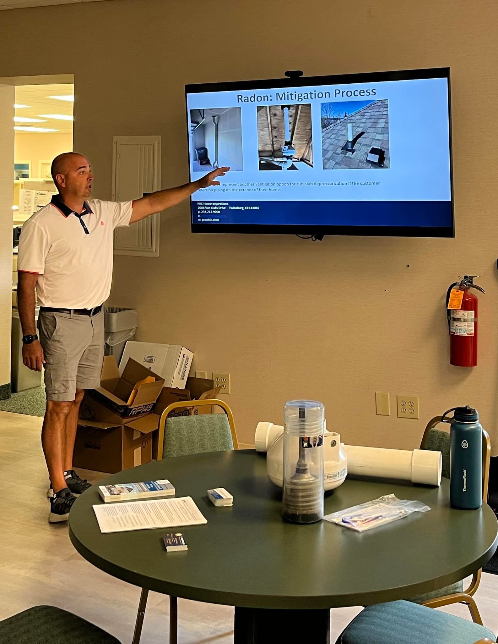 A man is giving a presentation in front of a large flat screen tv.
